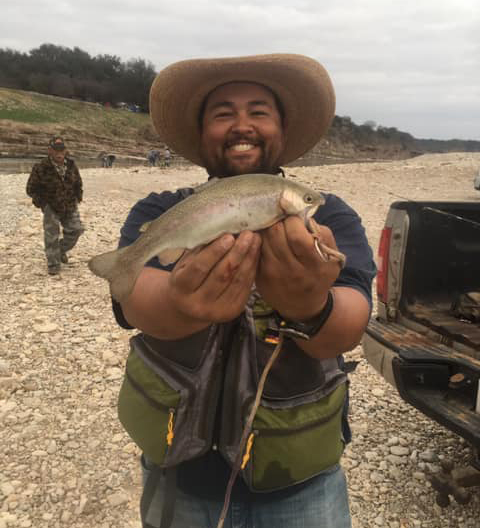 Angler holding two rainbow trout on a Llano River gravel bar